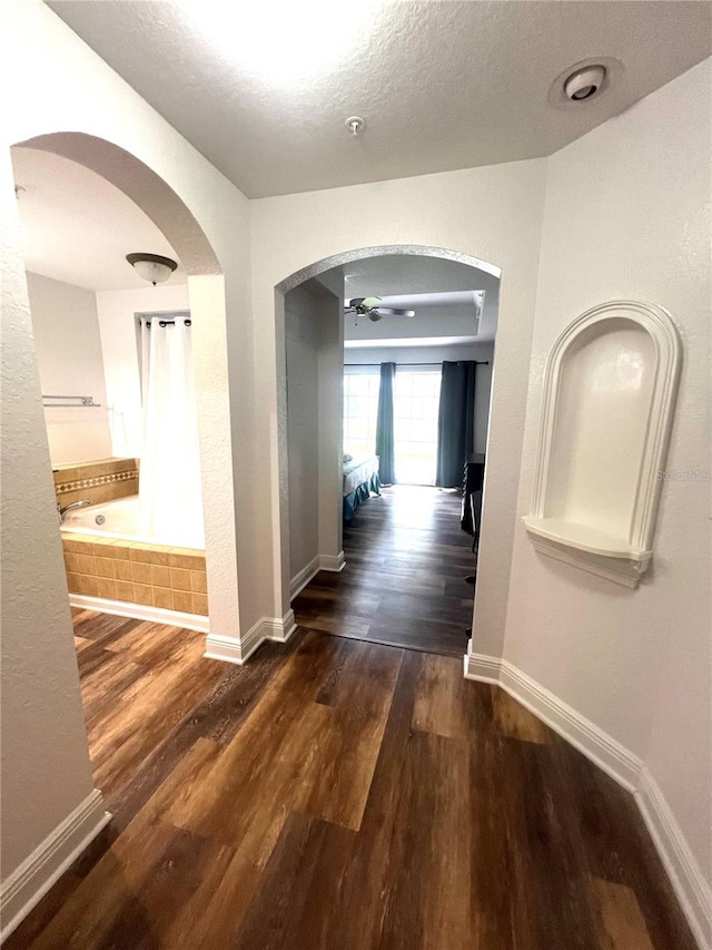 hallway with a textured ceiling and dark wood-type flooring