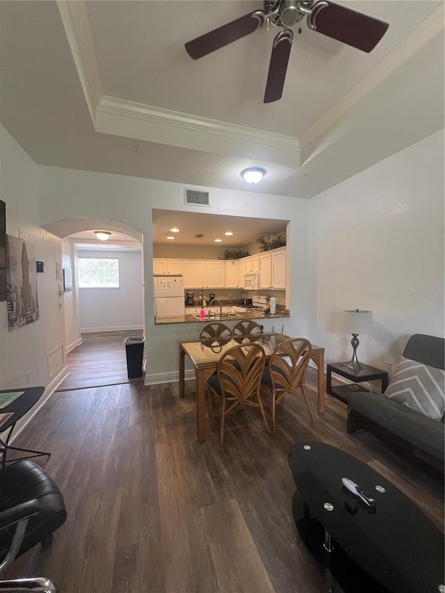 dining area with a raised ceiling, dark hardwood / wood-style floors, and crown molding