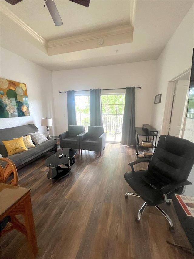 living room featuring a raised ceiling, crown molding, dark hardwood / wood-style flooring, and ceiling fan