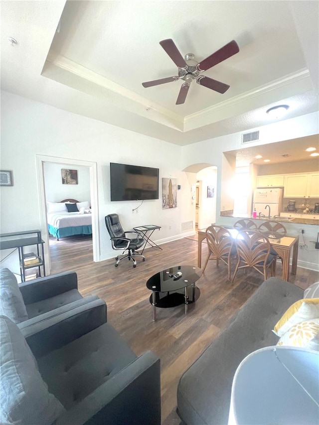 living room featuring ceiling fan, hardwood / wood-style flooring, and a raised ceiling