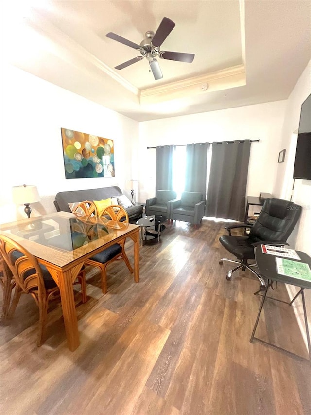 living room featuring ceiling fan, dark hardwood / wood-style floors, and a raised ceiling