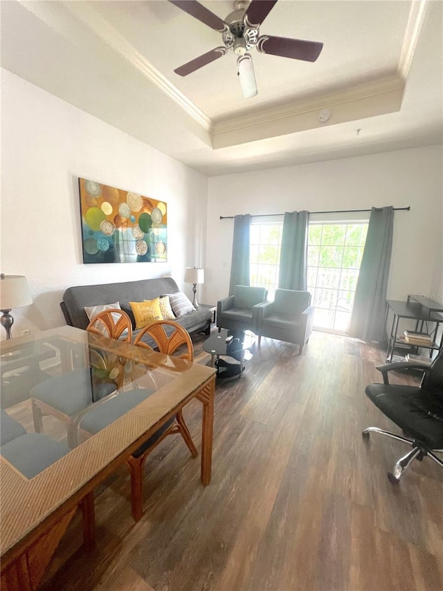 living room with a raised ceiling, crown molding, hardwood / wood-style flooring, and ceiling fan