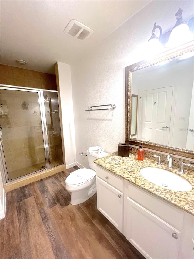 bathroom featuring hardwood / wood-style flooring, vanity, a shower with door, and toilet