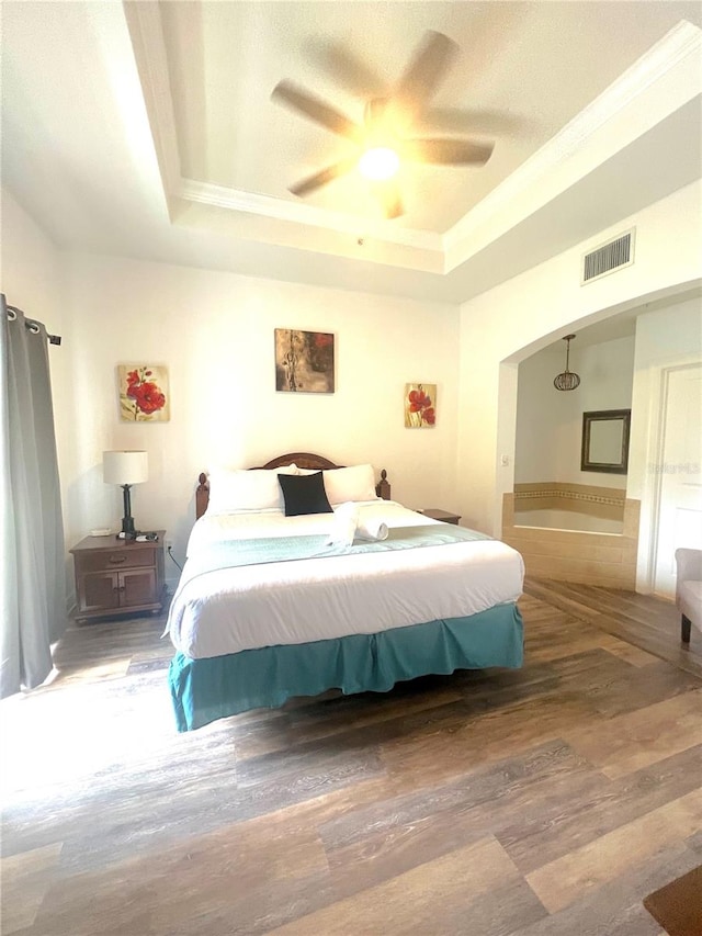 bedroom featuring a raised ceiling, hardwood / wood-style floors, and ceiling fan