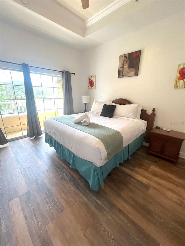 bedroom with ceiling fan, ornamental molding, a tray ceiling, and dark wood-type flooring