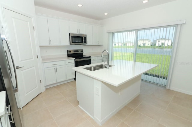 kitchen featuring an island with sink, white cabinets, sink, light tile patterned flooring, and appliances with stainless steel finishes