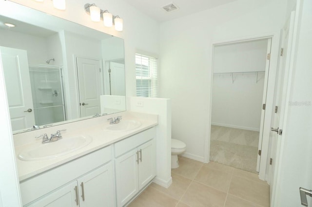 bathroom featuring tile patterned flooring, a shower with shower door, vanity, and toilet