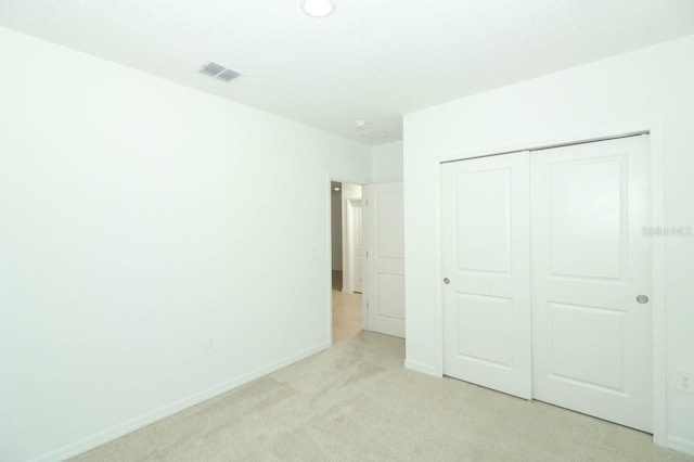 unfurnished bedroom featuring a closet and light colored carpet