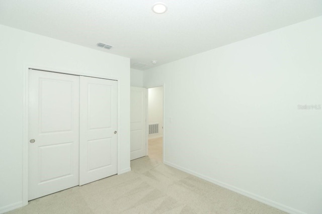 unfurnished bedroom with light carpet and a closet