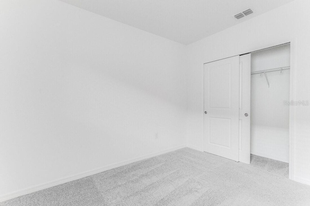 unfurnished bedroom featuring light carpet and a closet