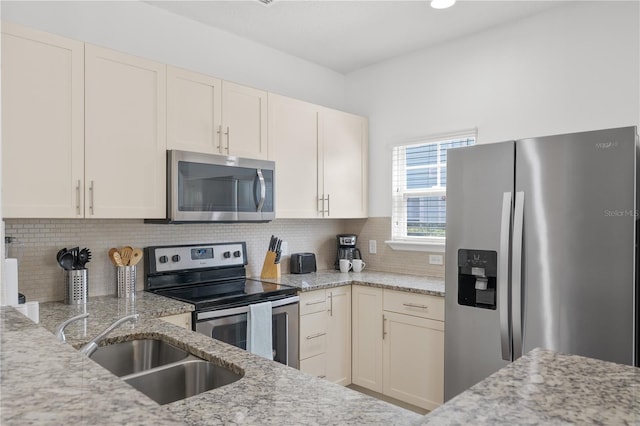 kitchen with stainless steel appliances, decorative backsplash, light stone counters, and sink