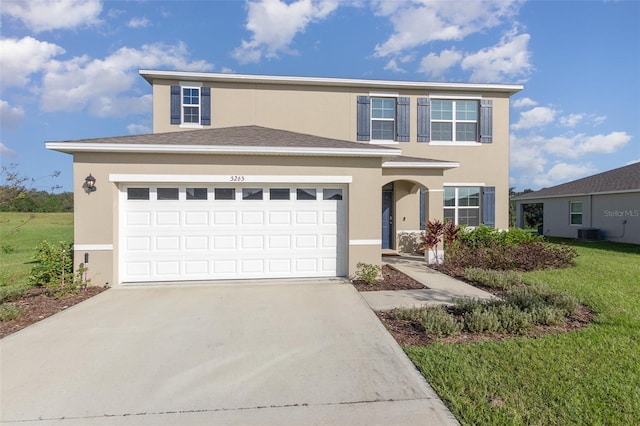 view of property featuring a garage, a front lawn, and central AC unit