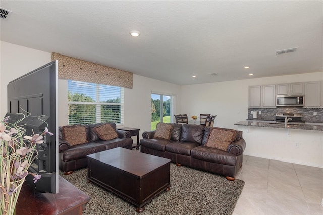 tiled living room with sink and a textured ceiling