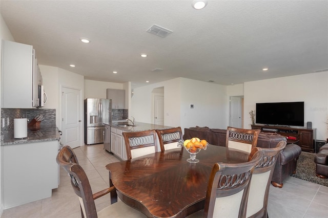 dining space with light tile patterned flooring, sink, and a textured ceiling