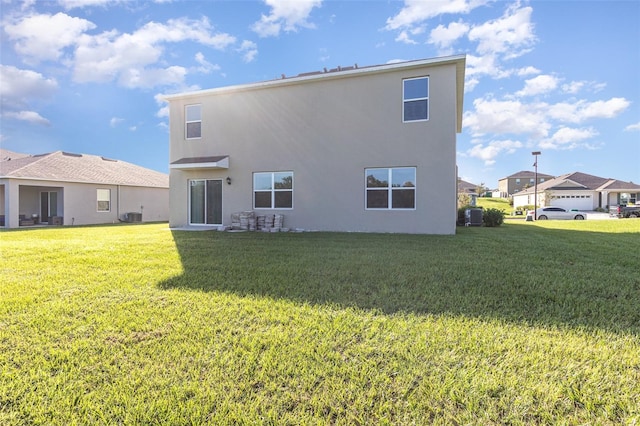 back of property with a garage, a lawn, and central air condition unit