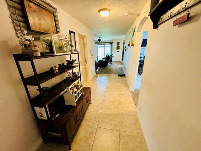 hallway featuring light tile patterned floors and a textured ceiling