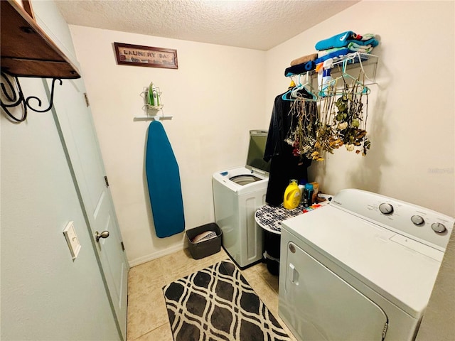 laundry room featuring a textured ceiling, light tile patterned floors, and washing machine and dryer