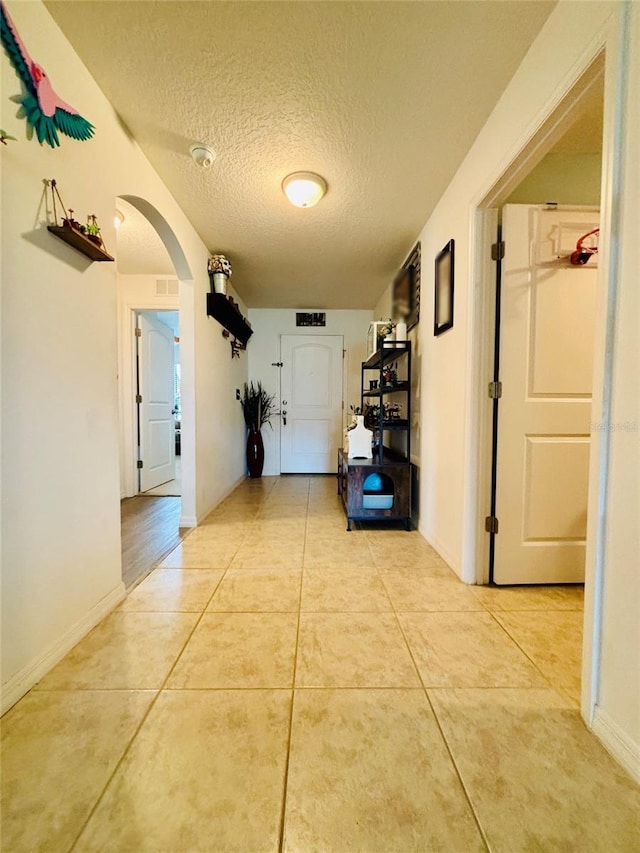 hall with light tile patterned flooring and a textured ceiling