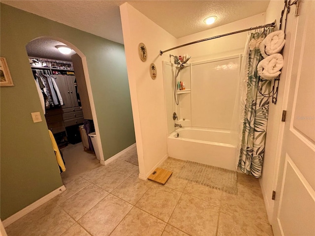 bathroom featuring a textured ceiling, shower / bath combo with shower curtain, and tile patterned floors