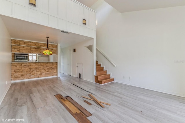 unfurnished living room featuring light hardwood / wood-style flooring and a high ceiling