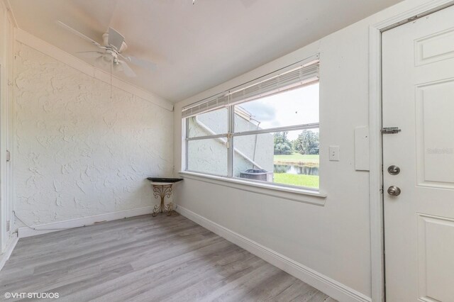 spare room featuring vaulted ceiling, light hardwood / wood-style flooring, a water view, and ceiling fan