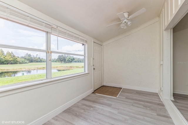 unfurnished sunroom featuring a water view and ceiling fan