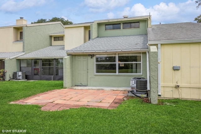 rear view of house with a patio area, central AC, a lawn, and a sunroom