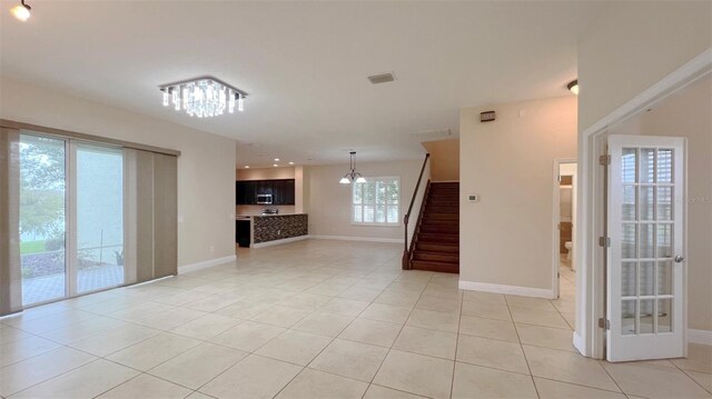 unfurnished living room featuring a notable chandelier and light tile patterned floors