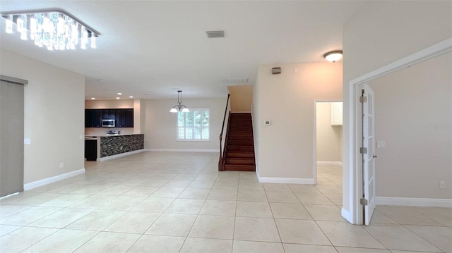 unfurnished living room featuring light tile patterned floors and an inviting chandelier