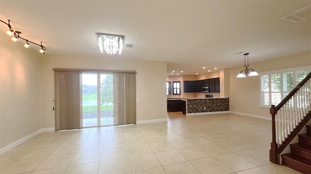 tiled empty room with a notable chandelier