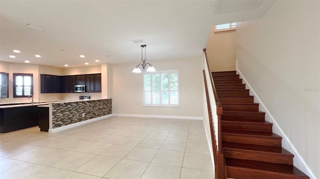 kitchen featuring light tile patterned flooring, plenty of natural light, an inviting chandelier, and kitchen peninsula