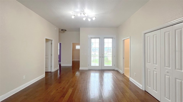 interior space featuring dark wood-type flooring, a textured ceiling, a closet, and french doors