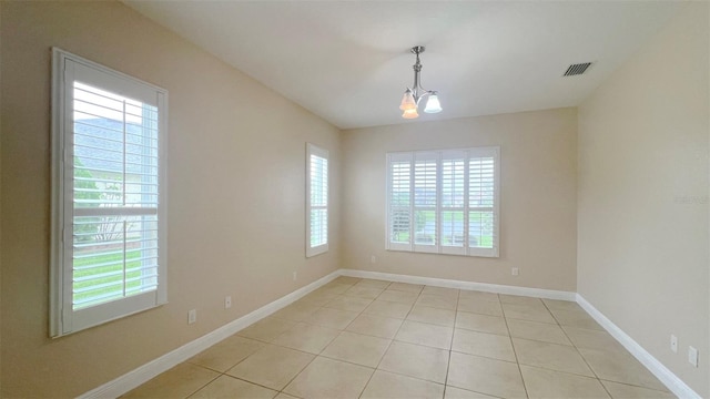 empty room featuring a chandelier and light tile patterned floors