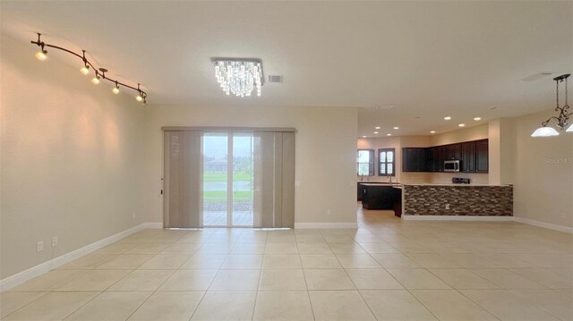 unfurnished room featuring light tile patterned flooring, an inviting chandelier, and a healthy amount of sunlight