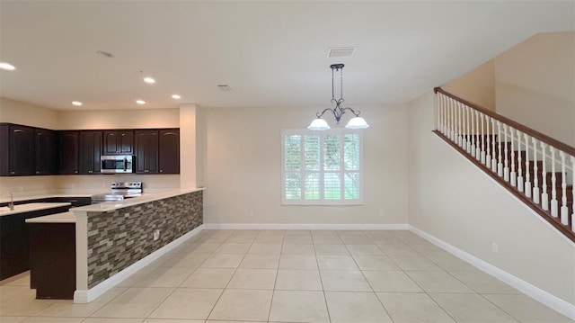 kitchen featuring pendant lighting, stainless steel appliances, a notable chandelier, and light tile patterned floors