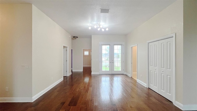 spare room featuring dark hardwood / wood-style floors, a textured ceiling, and french doors