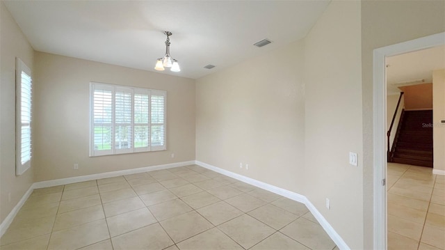 tiled empty room with a notable chandelier