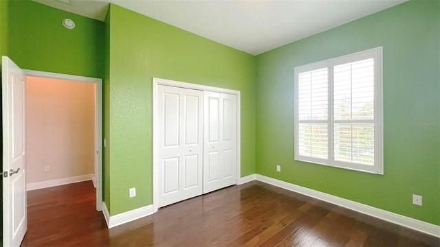 unfurnished bedroom featuring dark wood-type flooring and a closet