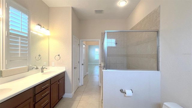 bathroom featuring vanity, tile patterned floors, toilet, and tiled shower