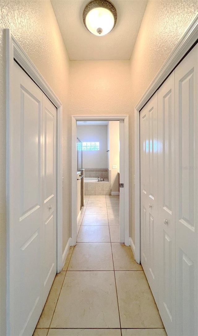 hall featuring a textured ceiling and light tile patterned floors