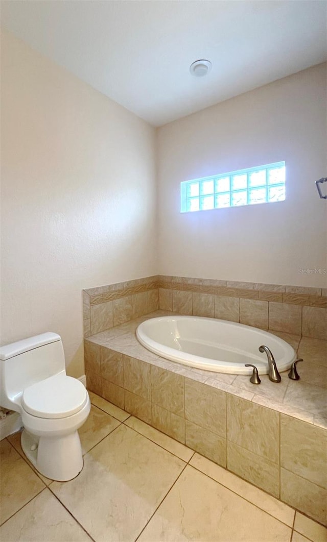 bathroom featuring toilet, a relaxing tiled tub, and tile patterned floors