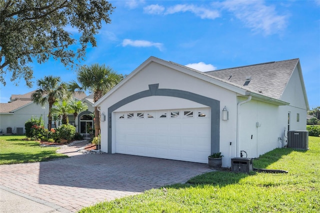 view of front of house with a front lawn, central AC unit, and a garage