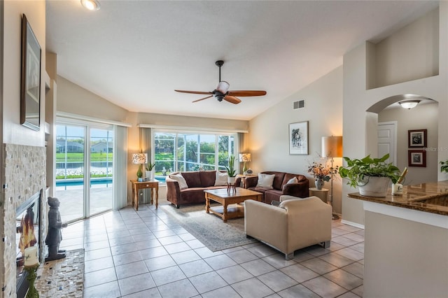 living room with light tile patterned flooring, high vaulted ceiling, a fireplace, and ceiling fan