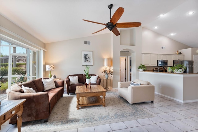 tiled living room featuring ceiling fan and high vaulted ceiling