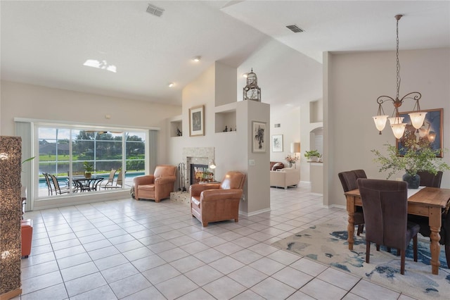 tiled living room with a chandelier, a tiled fireplace, and high vaulted ceiling