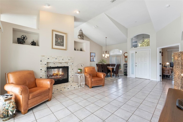 living room with an inviting chandelier, a tile fireplace, light tile patterned floors, and high vaulted ceiling