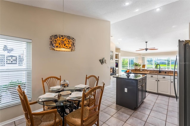 tiled dining area featuring lofted ceiling, sink, and ceiling fan