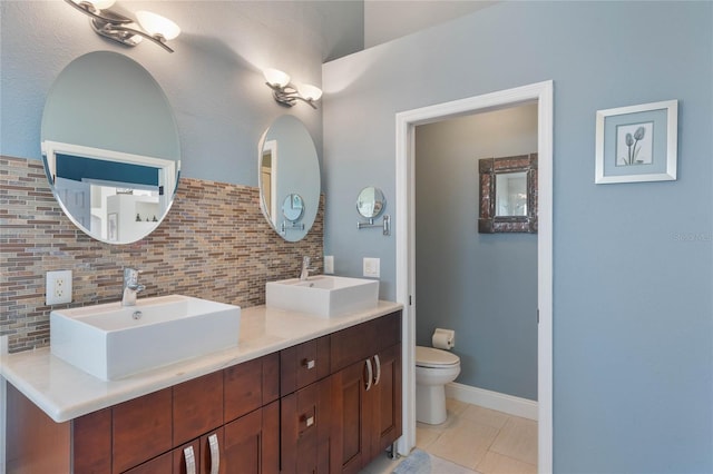 bathroom featuring tasteful backsplash, vanity, tile patterned flooring, and toilet