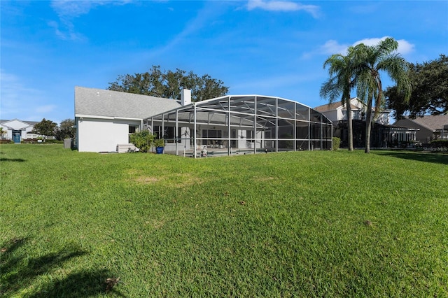 back of property with a yard and glass enclosure