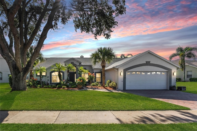 ranch-style house with a garage and a yard